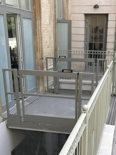 Metal railing beside a building, leading to a lightwell lift