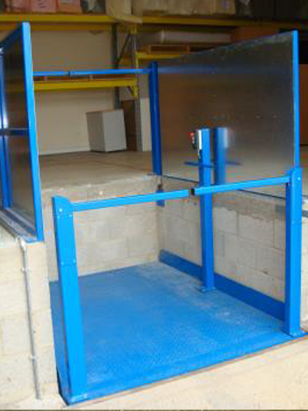Blue industrial loading lift with safety panels, installed in a warehouse setting with shelving in the background.